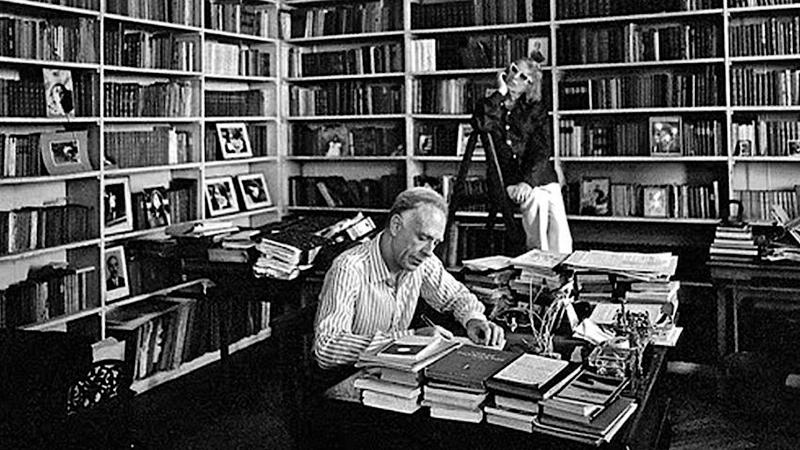 El escritor argentino Adolfo Bioy Casares escribiendo en su biblioteca, acompañado por su mujer, la también escritora Silvina Ocampo.